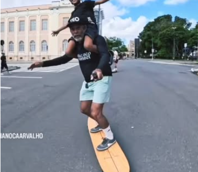Integrante da crew andando de longboard com os braços abertos, estilo surf